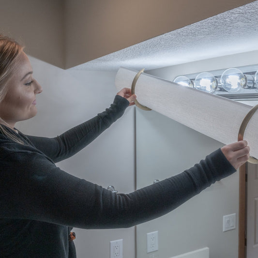 Showing a woman using a 30" linen EzLightWraps shade covering a 4 bulb Hollywood light