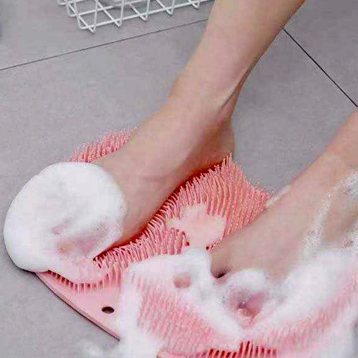Pink bath scrubber showing with foamy soap on a tile floor